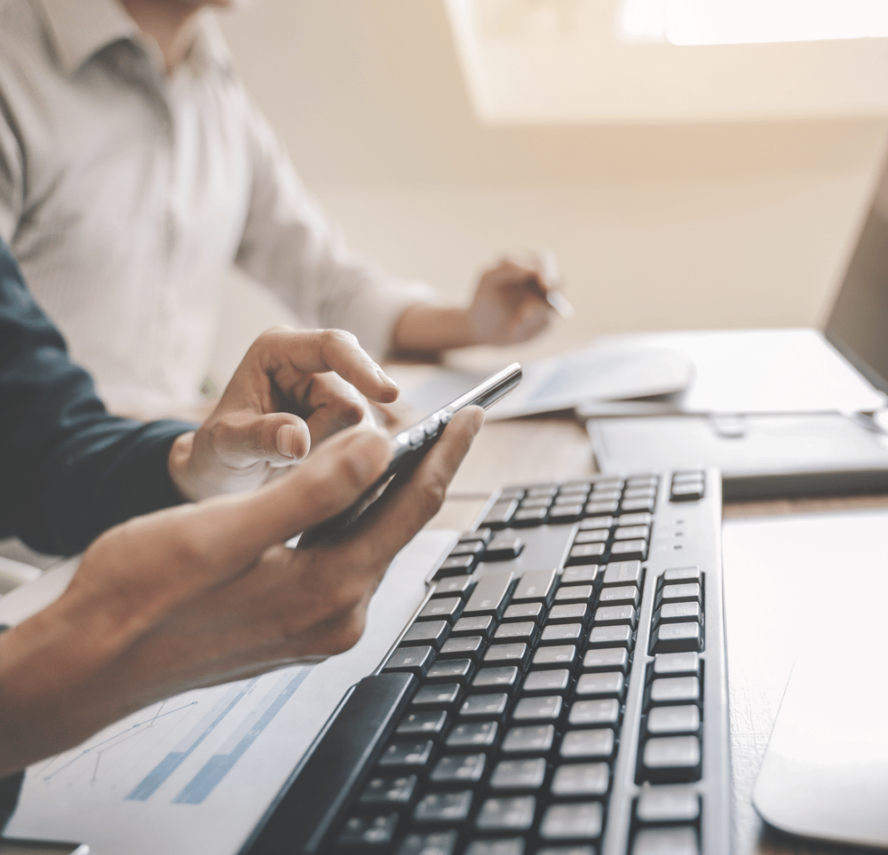 Universitätsmitarbeitende an ihren Schreibtischen nutzen Computer und Smartphones, um mit Studo Flow administrative Prozesse zu digitalisieren und zu vereinfachen