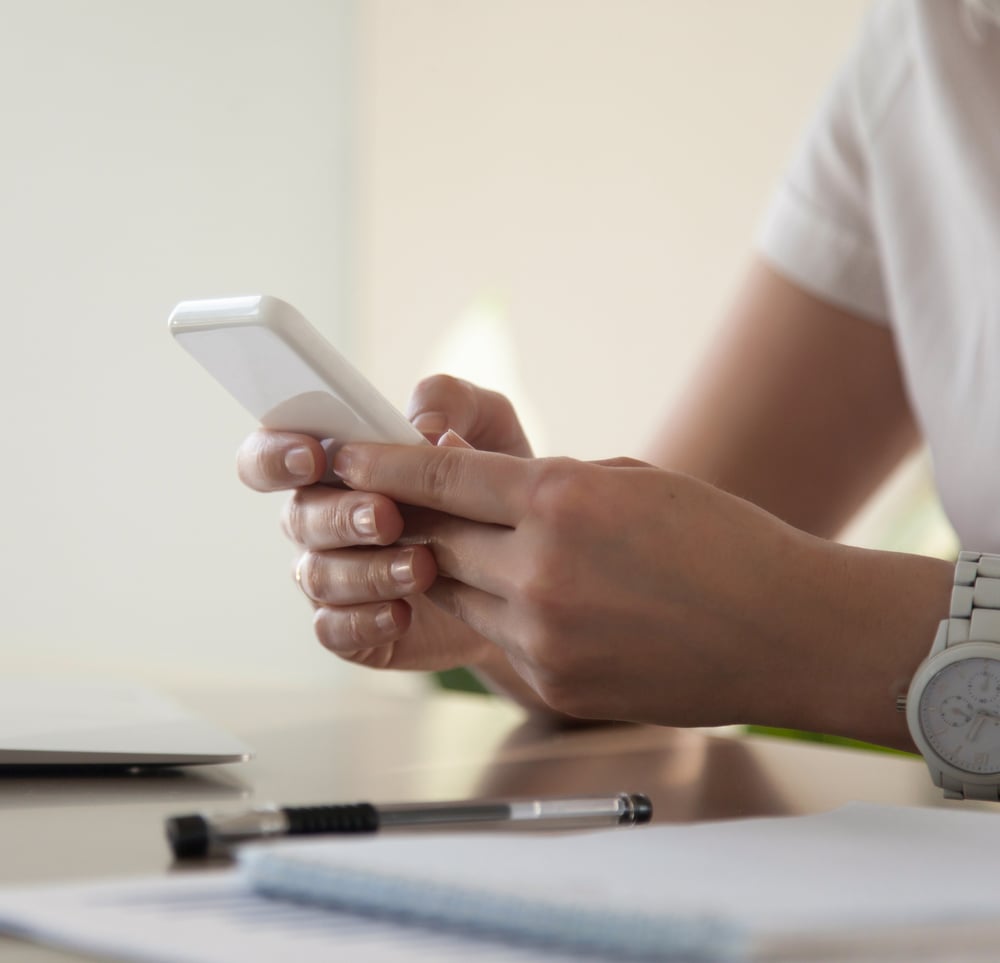 Psychologe oder Psychologin sitzt an einem Schreibtisch, hält ein Smartphone und chattet mit einem Studierenden über den Studo Mental Health Chat