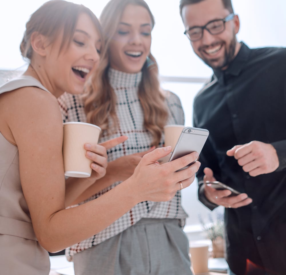 Universitätsmitarbeitende schauen gemeinsam begeistert auf ein Smartphone und nutzen die Studo Mitarbeitenden-App für schnellen mobilen Zugriff auf ihre Universitätssysteme